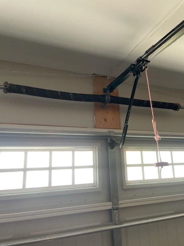 A garage door opener with a detached spring and hanging rope.
